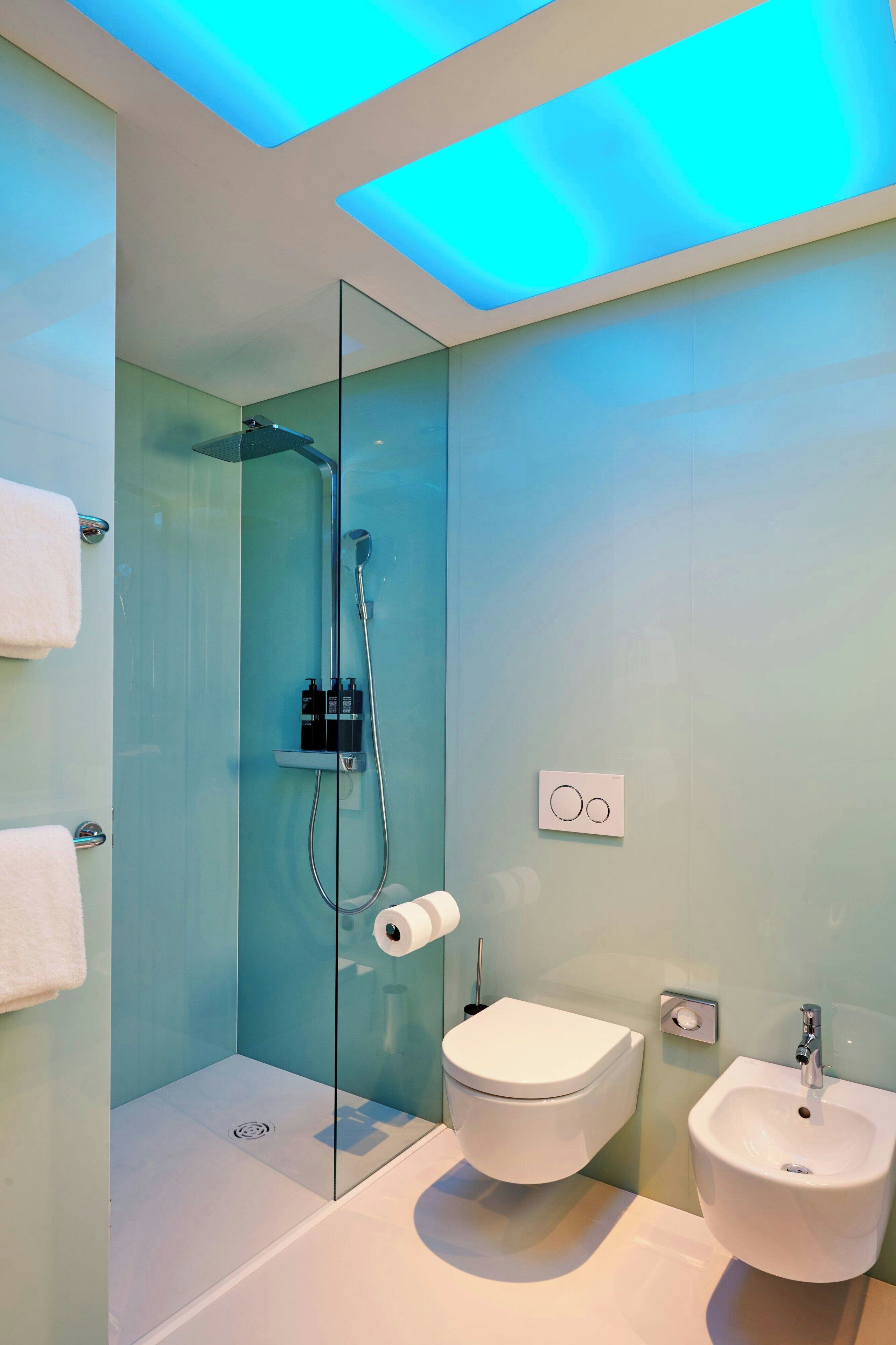 A modern bathroom with a glass-enclosed shower, a toilet, and a sink.
