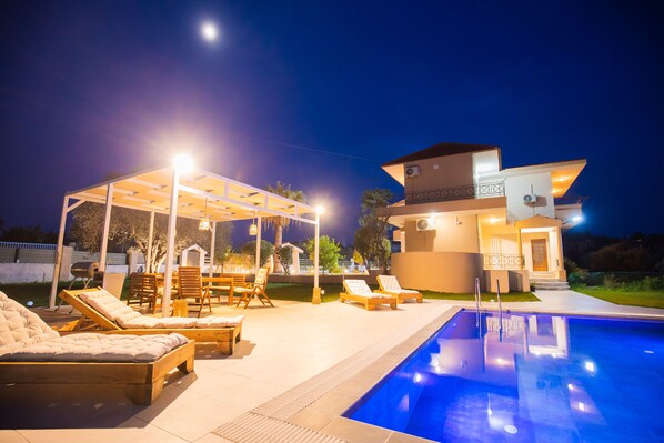 Relax by the pool surrounded by a patio with lounge chairs and a covered seating area.