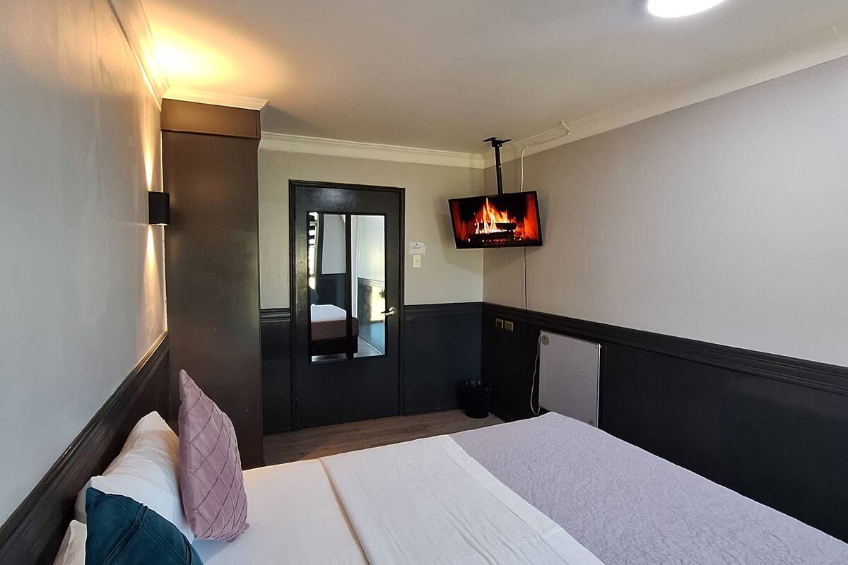 A hotel room with a large bed, a TV mounted on the wall, and a mirror above the door.