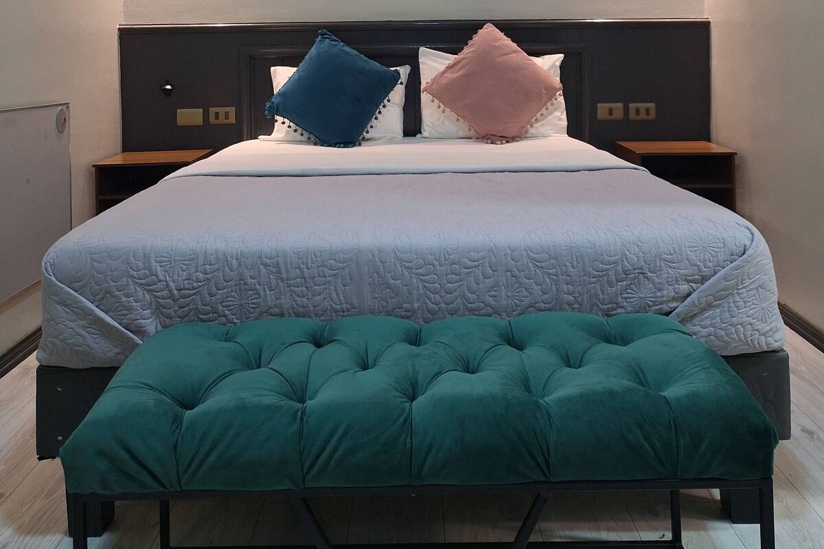 A neatly arranged bedroom with a large bed, two bedside tables, and a bench.