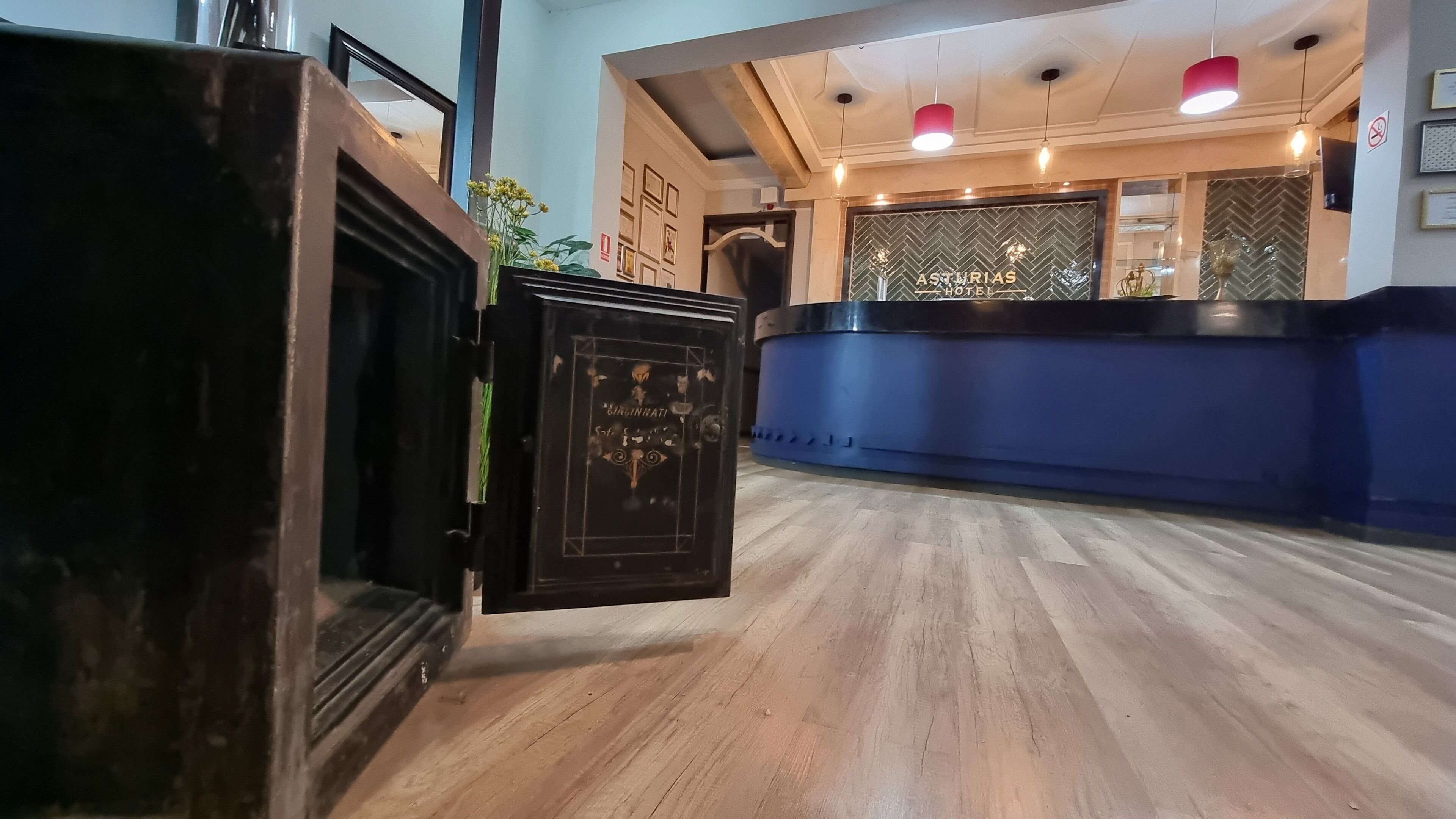 A reception area with a wooden floor, a blue counter, and a black safe.
