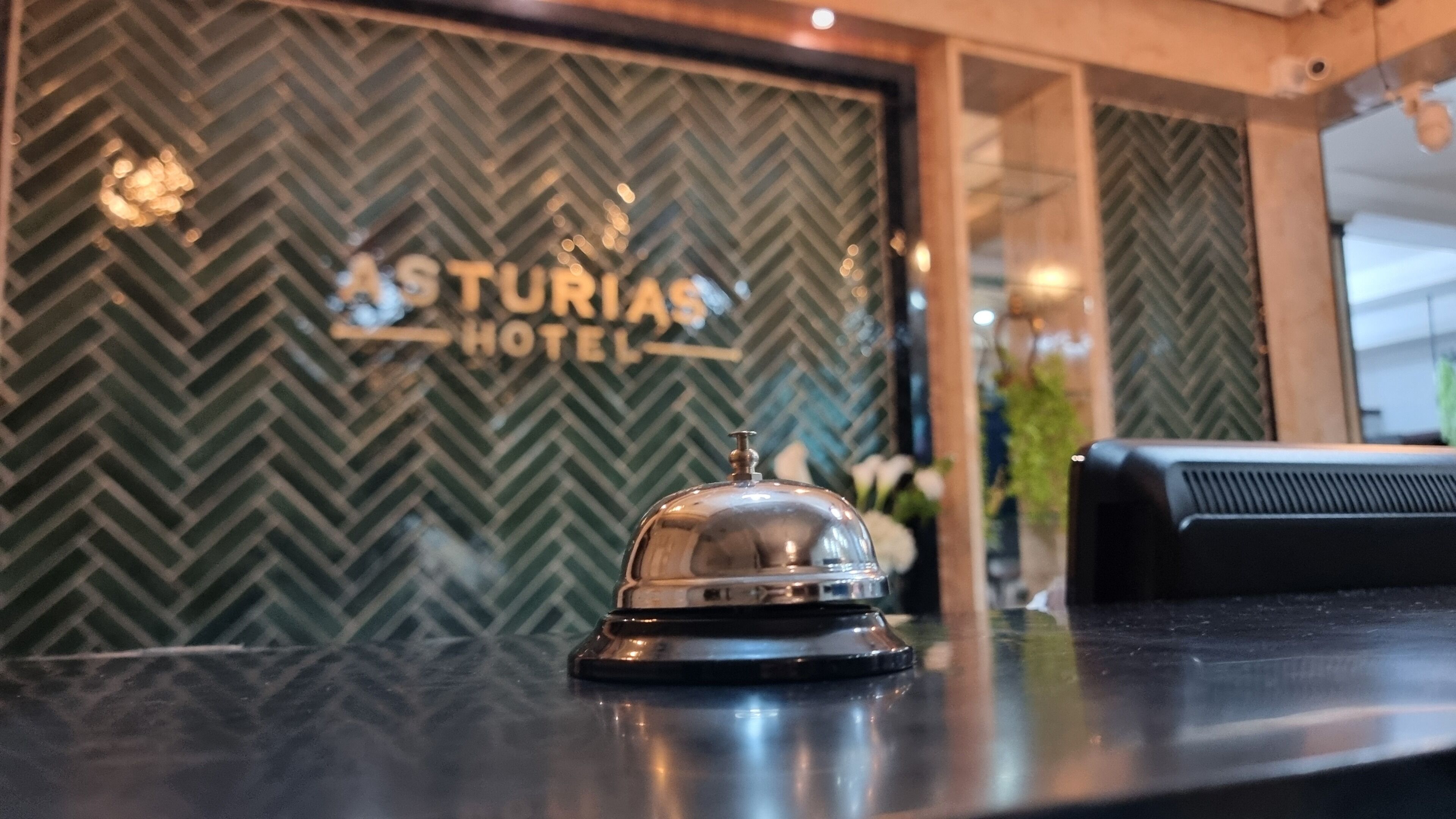 A hotel reception area with a herringbone-patterned wall and a reception desk.