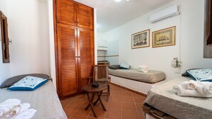 Una habitación con dos camas, un armario de madera, una mesita y una silla.