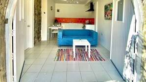 A living room with a blue sofa, a white coffee table, and a tiled floor. - Hibiscus cottage Marigot bay (Marigot bay)