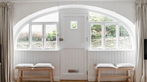 A room with a white door, two windows, and a bench. - Beautiful converted stable near the coast (Plymouth)