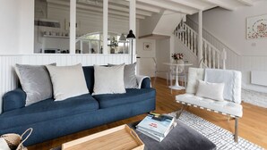 A modern living room with a blue sofa, white armchairs, and a wooden coffee table. - Beautiful converted stable near the coast (Plymouth)
