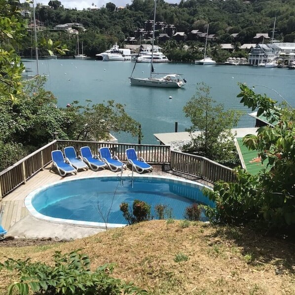 A swimming pool with lounge chairs, surrounded by greenery, overlooking a marina with boats. - Green Fig Cottage Marigot Bay. (Marigot bay)