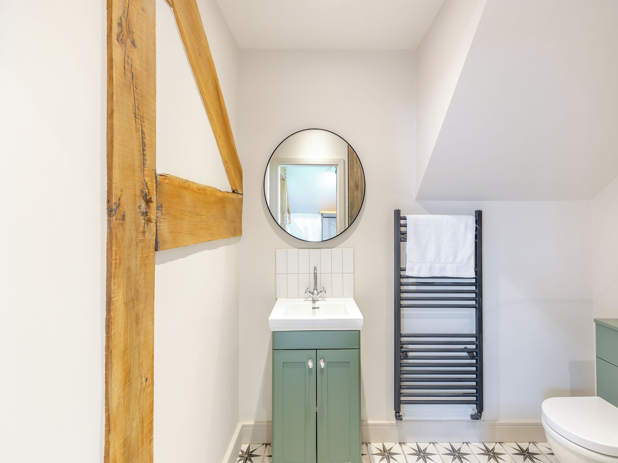 A bathroom with a white sink, a mirror, a towel rack, and a toilet.