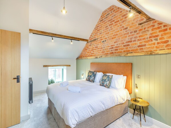 A bedroom with a brick ceiling, a bed with white linens, a bedside table, and a radiator.