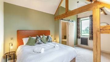 A bedroom with a wooden ceiling, a bed with white linens, and a bedside table with a lamp.