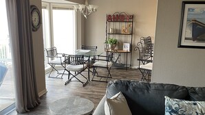 Ein geräumiges Wohnzimmer mit grauem Sofa, einem runden Couchtisch und einem Essbereich mit einer Chandelier.