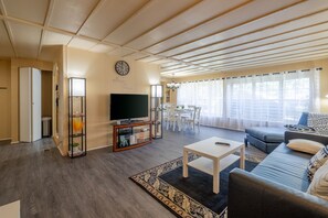 Una sala de estar con sofá, televisor y un comedor con mesa y sillas.