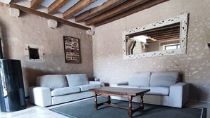 Una sala de estar con techo de madera, un juego de sofá, una mesa de centro y un espejo en la pared.