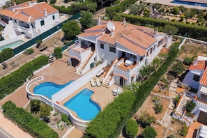 Una amplia villa con piscina, varios balcones y un jardín bien cuidado.