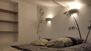Une chambre à coucher avec un lit, une étagère fixée au mur et des œuvres d’art murales.