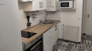 Une cuisine de taille réduite avec des meubles blancs, un four à micro-ondes, un évier et un lave-vaisselle.