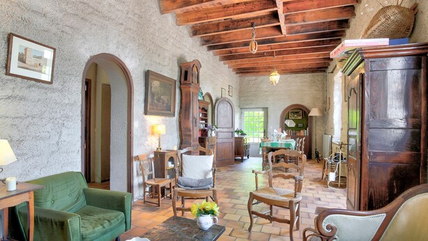 A rustic room with wooden furniture, a green armchair, a wooden cabinet, and a tiled floor. - La Grangerie - Charmante demeure typique (Erquy)