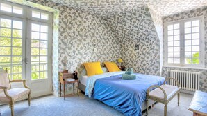 A bedroom with a bed, two chairs, a table, and a window. - La Grangerie - Charmante demeure typique (Erquy)
