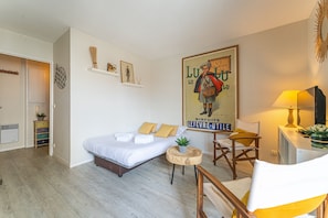 Un dormitorio con cama, mesita de noche, silla y un cartel en la pared.