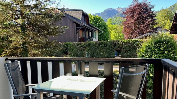 Un balcón con mesa y sillas, con vistas a un paisaje montañoso.