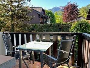 A balcony with a table and chairs, overlooking a mountainous landscape.