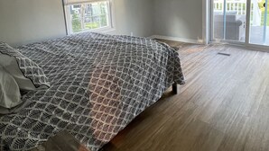 A bedroom with a bed, a ceiling fan, a TV mounted on the wall, and a view through a sliding glass door. - Minutes to the Beach with a hot tub and decks for relaxing. (Ocean View)