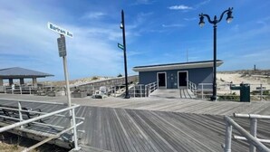 En træpromenade fører hen til en lille bygning med fladt tag, et skilt der siger "Barilam Ave", og en lygtepæl.
