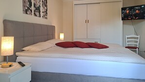 Un dormitorio con una cama, una mesita de noche, una lámpara, un armario y un televisor.