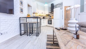 A modern kitchen with white cabinets, a black countertop, and a hanging light fixture. - Moderno y elegante ap. Barrio Ibiza MEN30 (Madrid)