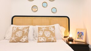 A neatly made bed with white linens, two pillows with a seashell and starfish pattern, and a framed Picasso painting on a bedside table. - Moderno y elegante ap. Barrio Ibiza MEN30 (Madrid)