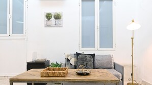 A living room with a sofa, a coffee table, a floor lamp, and a wall-mounted plant. - Moderno y elegante ap. Barrio Ibiza MEN30 (Madrid)