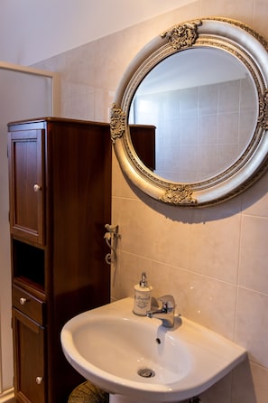 Un baño con un mueble de madera, un lavabo blanco y un espejo decorativo.