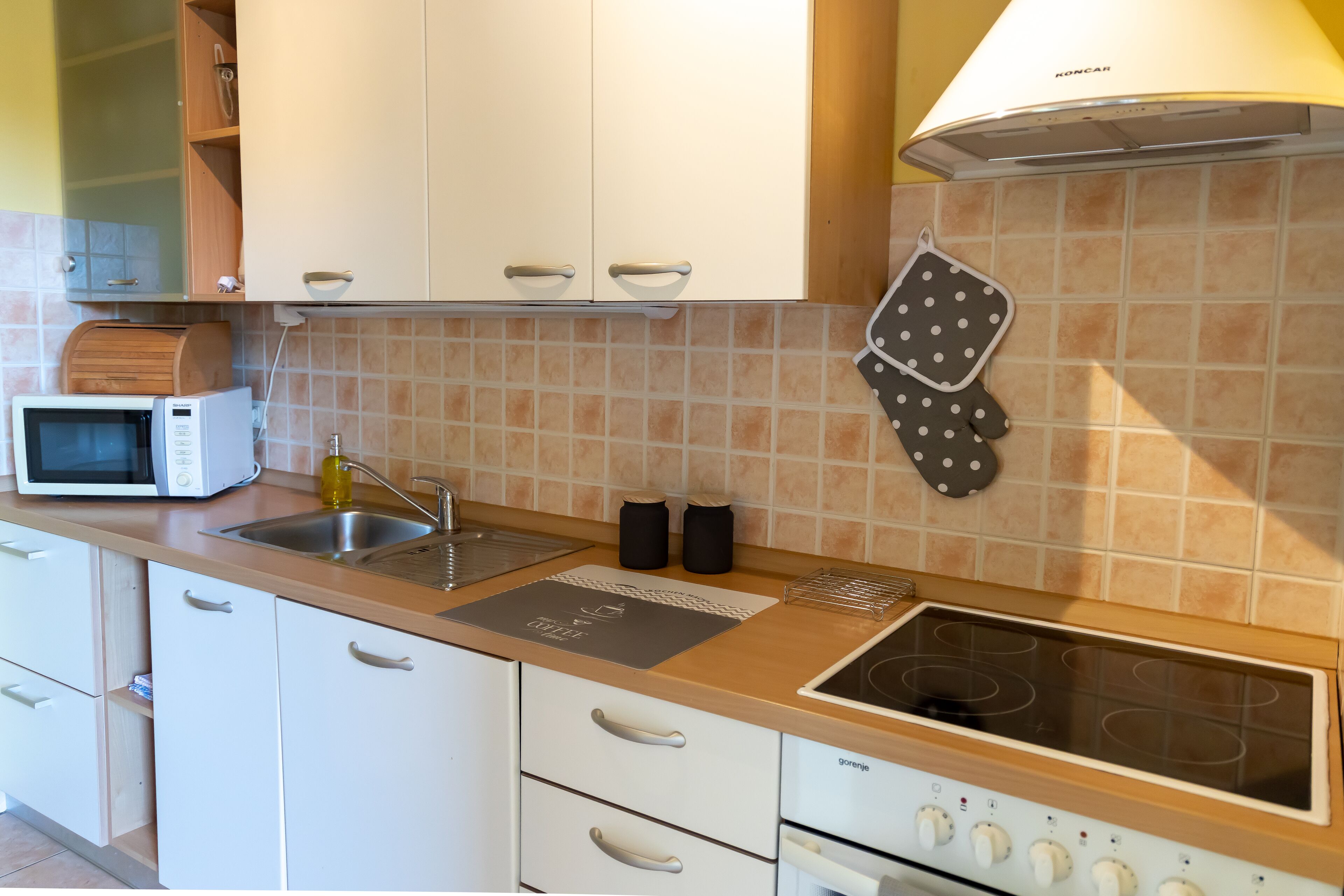 A modern kitchen with white cabinets, a microwave, a gas stove, and a sink.