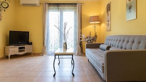 Una sala de estar con televisor, sofá y una mesa con adornos.