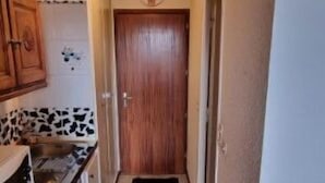 A narrow hallway with a wooden floor leading to a door. - Studio 4 Pers, vue Magnifique à 150 m des Pistes (Montvalezan)
