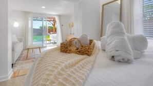 A hotel room with a bed, a large mirror, a wicker basket, and a view of the outdoors. - Surf Shack! Pool table! Fire Pit! 10 min to beach! (Martin County)