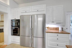 A modern kitchen with white cabinetry, stainless steel appliances, and a granite countertop. - Surf Shack! Pool table! Fire Pit! 10 min to beach! (Martin County)