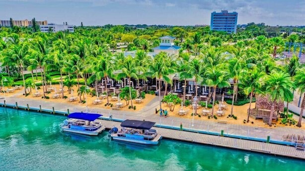 A waterfront hotel with a dock, palm trees, and a building with a blue roof. - Surf Shack! Pool table! Fire Pit! 10 min to beach! (Martin County)