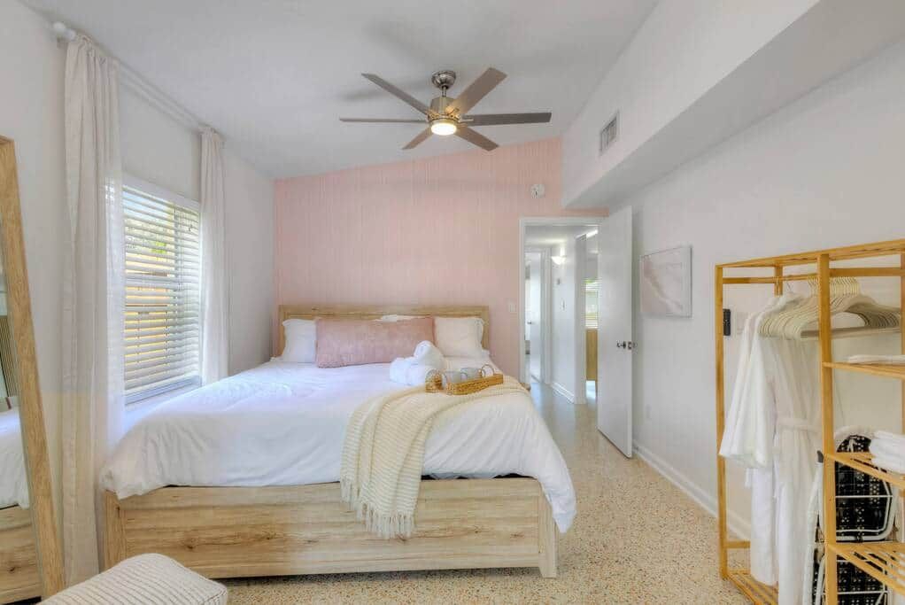 A bedroom with a bed, a ceiling fan, a walk-in closet, and a door leading to another room.