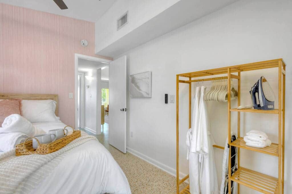 Une chambre à coucher avec un lit, une armoire en bois et un couloir menant à une autre pièce.