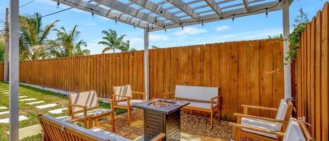 A covered patio with wooden furniture and a fire pit.