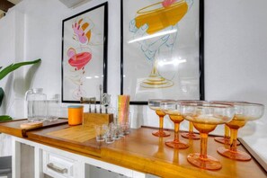 A bar area with a wooden counter, clear glasses, and a bottle of water. - Surf Shack! Pool table! Fire Pit! 10 min to beach! (Martin County)
