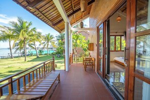 A wooden balcony with a view of the sea and palm trees. - Lotus Home (Phu Quoc)