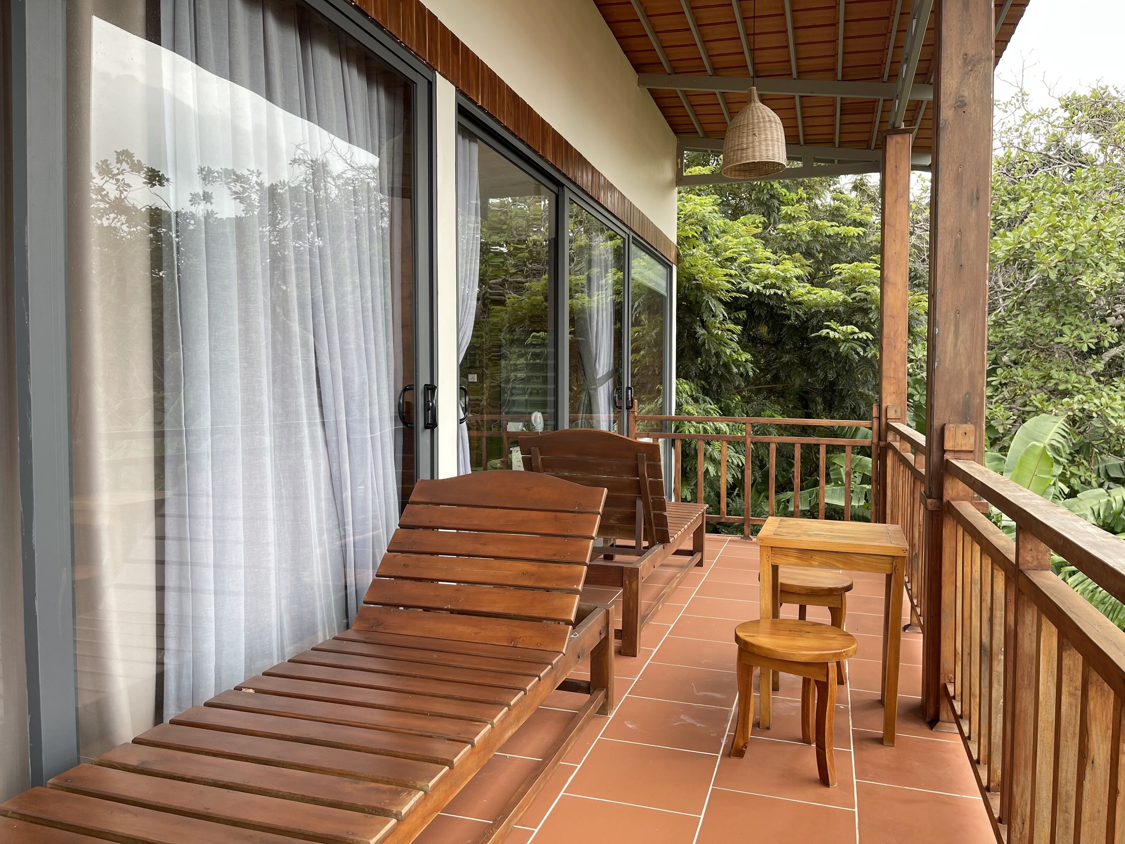 A balcony with wooden furniture, including a sofa and chairs, and a small table.