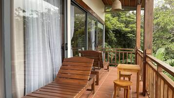 A balcony with wooden furniture, including a sofa and chairs, and a small table.