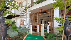 Un edificio moderno con una escalera en espiral, plantas de interior y un sendero alfombrado en color verde.