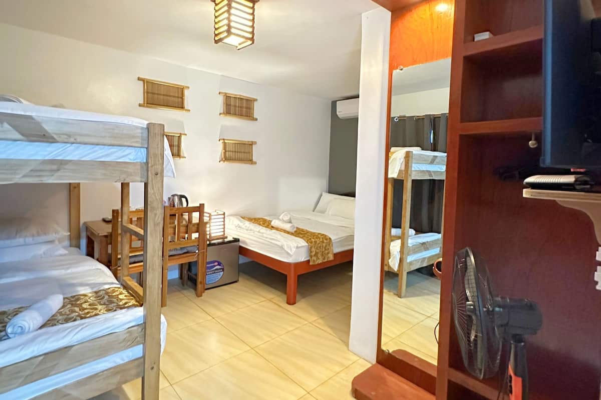Une chambre de dortoir équipée de lits superposés, d’un bureau, d’une chaise, d’un petit réfrigérateur et d’un téléviseur.