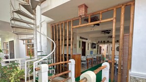 Una escalera de caracol con cubierta de madera y césped artificial verde que conduce a un espacio exterior con estructura de bambú.