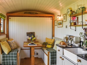 A cozy kitchen with a bench seating area, a wooden table, and a clock on the wall.
