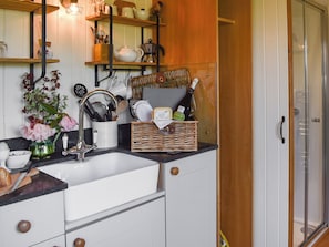 Una cocina con un lavamanos, armarios y una puerta de madera.